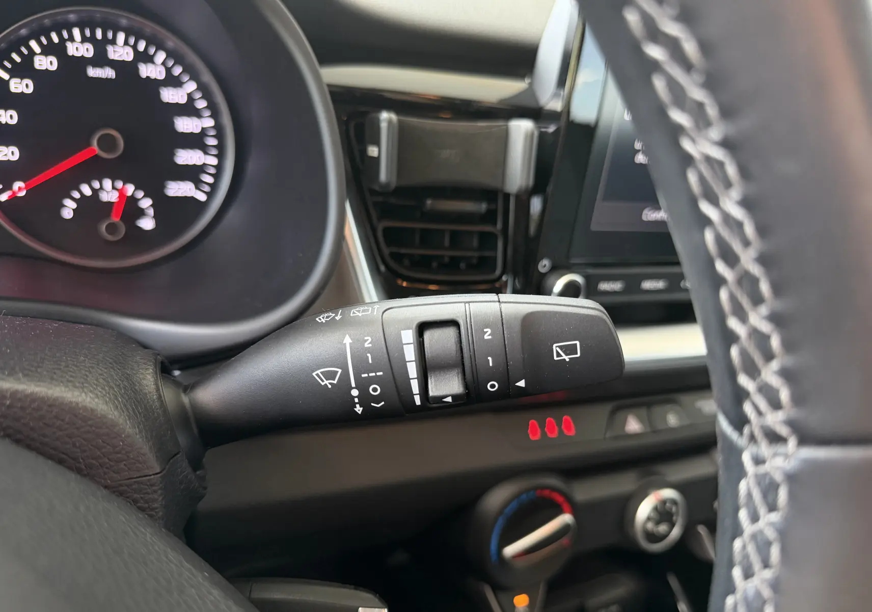 Gros plan sur la commande d’essuie-glace à gauche du volant dans l’habitacle noir du Kia Stonic blanc 2022.