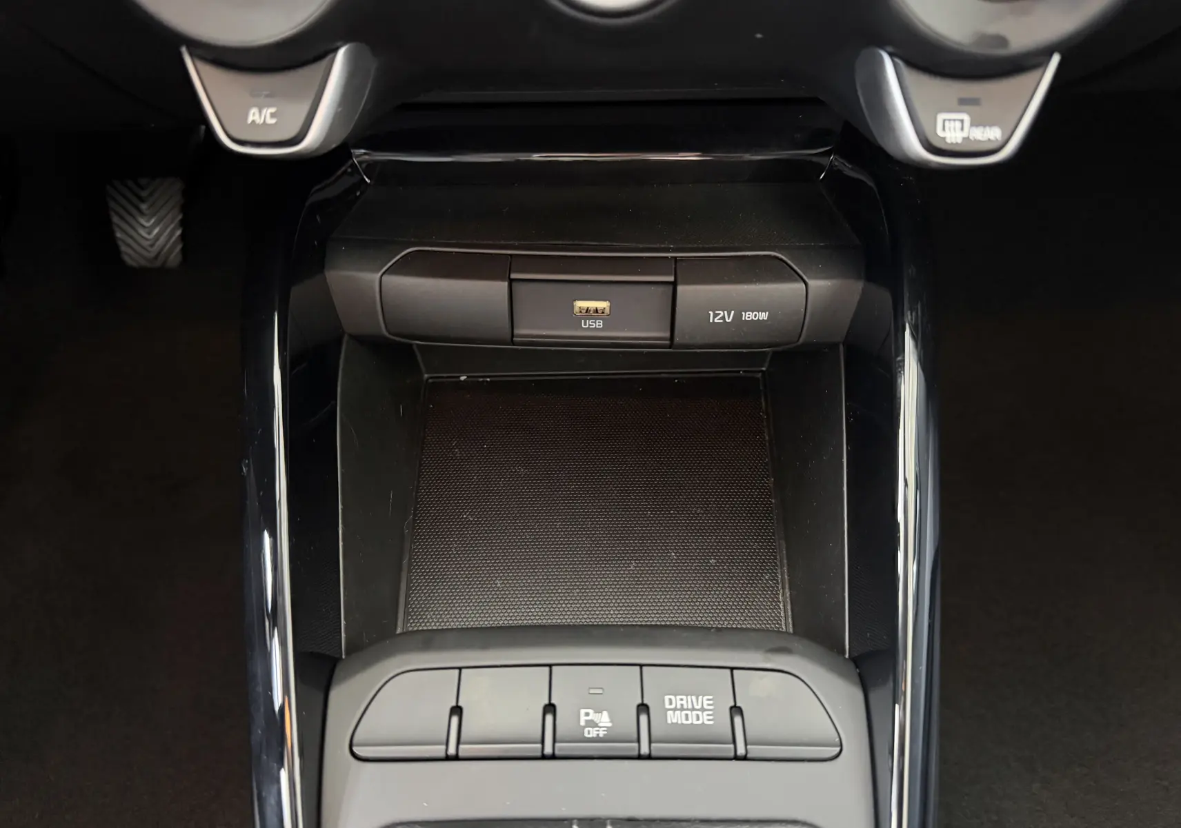 Vue rapprochée de la console centrale noire du Kia Stonic 2022, avec port USB, prise 12V et boutons Drive Mode.