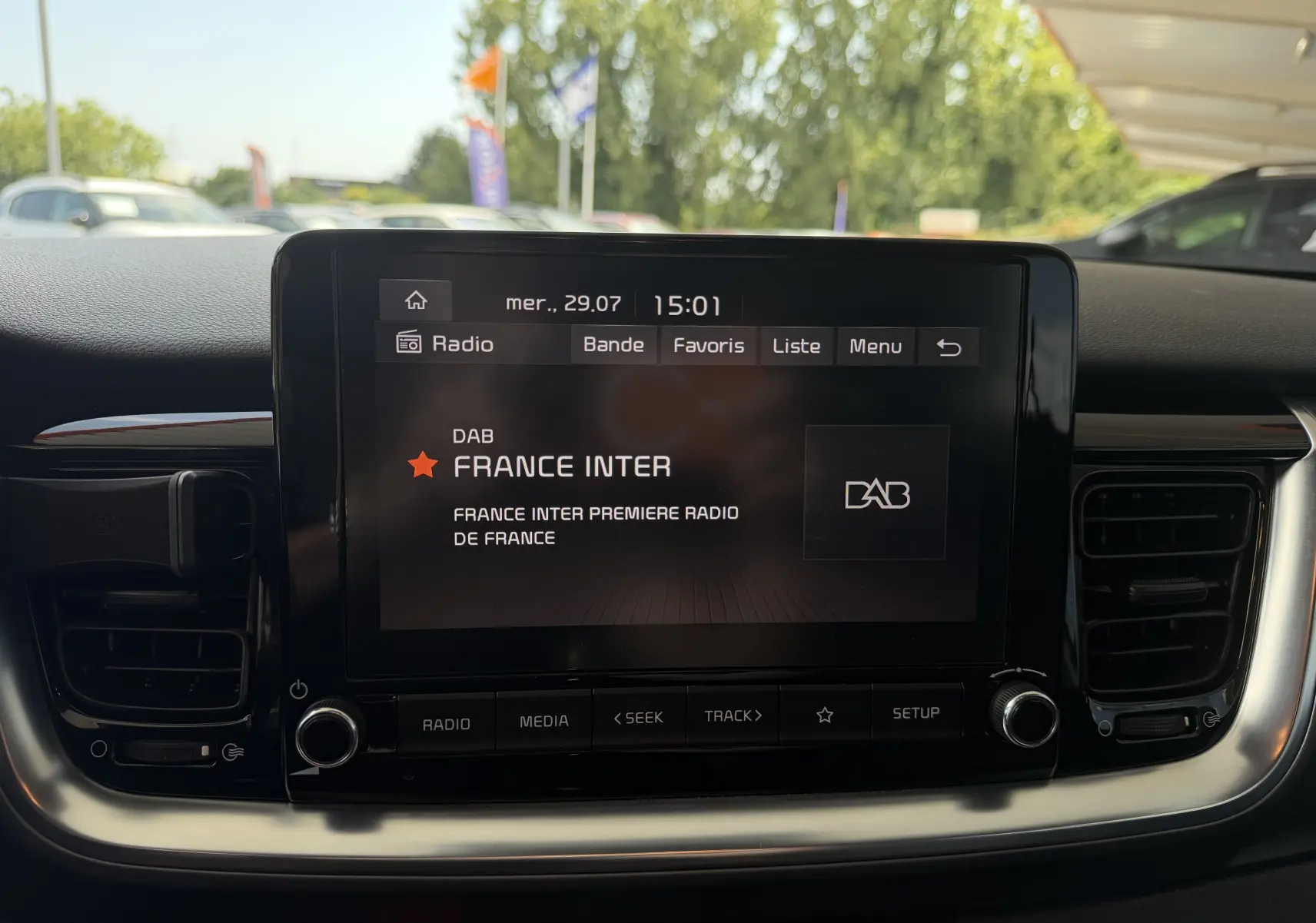 Écran tactile central du tableau de bord du KIA Stonic blanc, affichant la radio France Inter en extérieur jour.