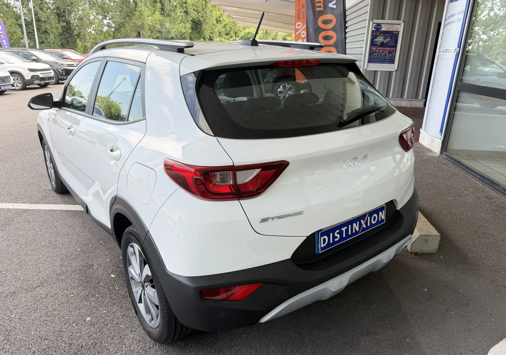Vue 3/4 arrière droite d'un KIA Stonic blanc 2022 avec toit noir et badge distinctif sur le hayon.