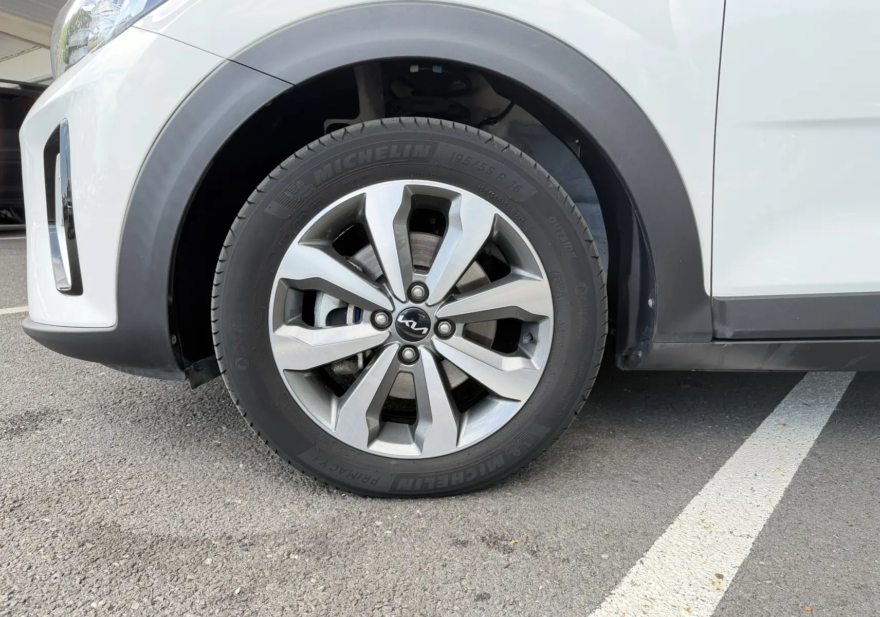 Gros plan sur la roue avant gauche d’un KIA Stonic blanc avec jante alliage et pneu Michelin.