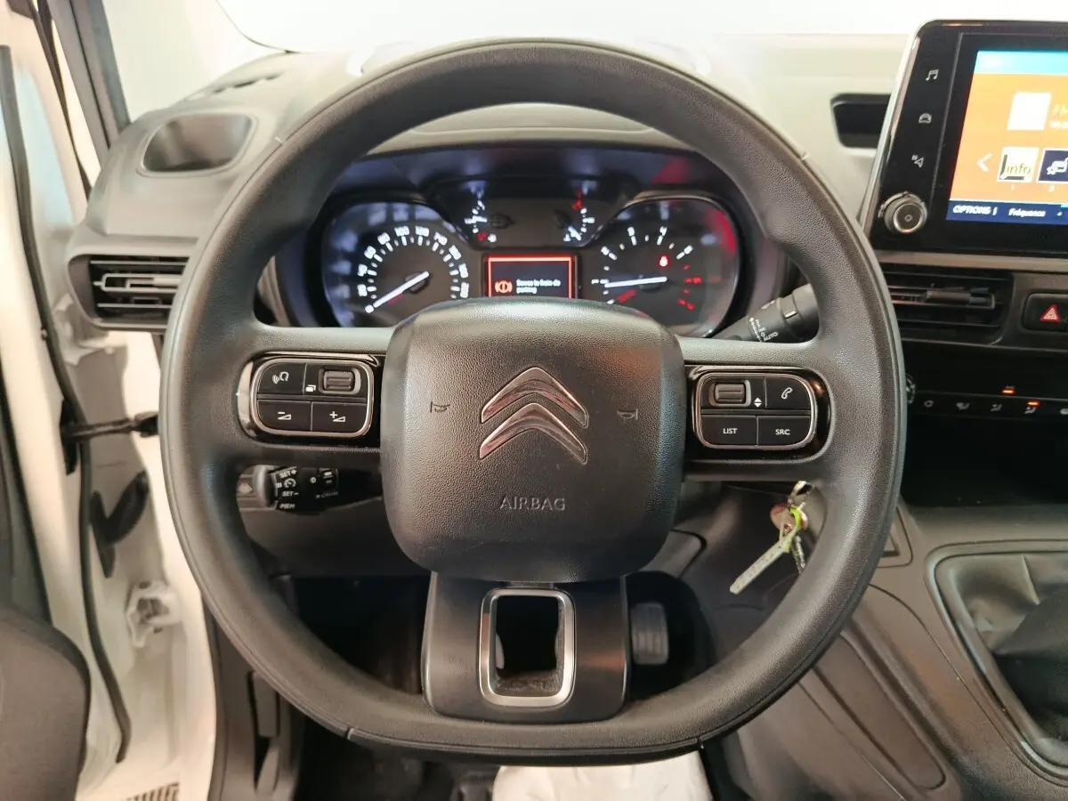Vue centrée sur le volant multifonctions noir du Citroën Berlingo blanc, avec tableau de bord et écran tactile visibles.