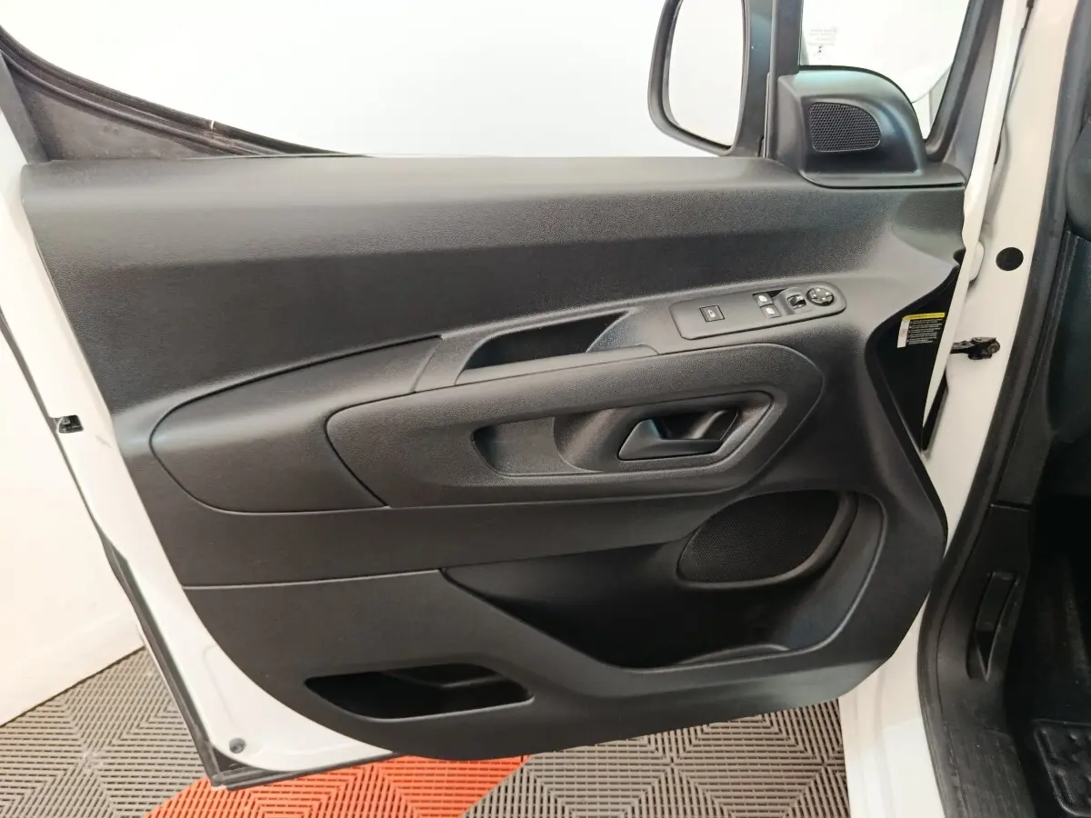 Vue rapprochée de la porte avant gauche noire du Citroën Berlingo blanc, avec commandes électriques des vitres et rétroviseur.