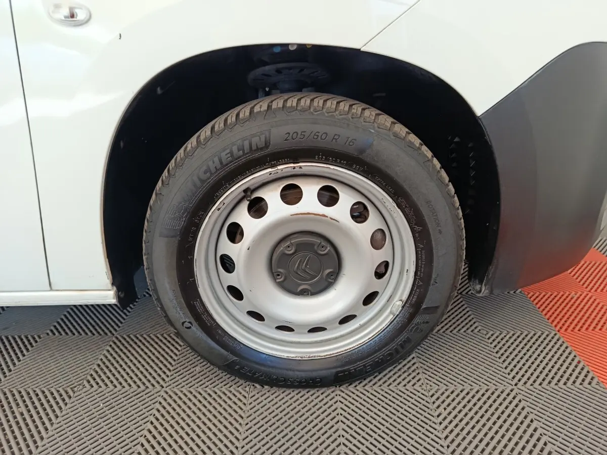 Gros plan sur la roue avant droite blanche en jante acier du Citroën Berlingo blanc, avec logo central visible.