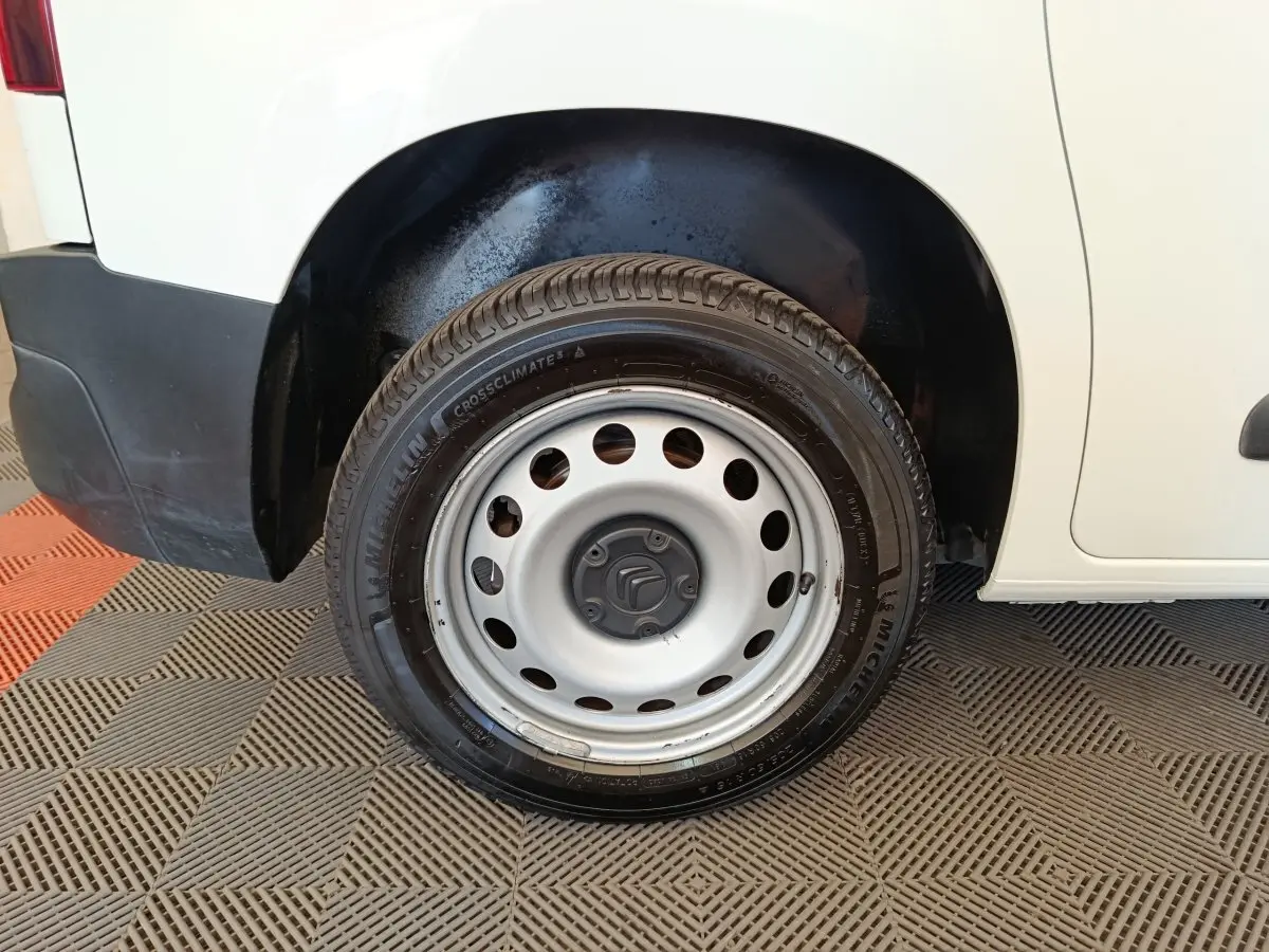 Gros plan sur la roue arrière droite en jante acier du Citroën Berlingo blanc, avec partie basse de la carrosserie visible.