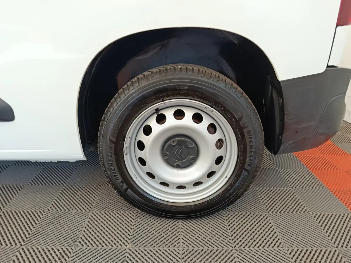 Gros plan sur la roue arrière droite en jante acier grise du Citroën Berlingo blanc, avec logo Citroën au centre.