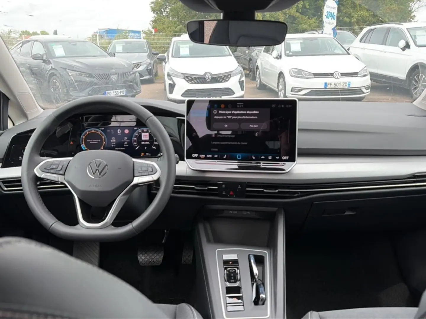 Vue intérieure de face du tableau de bord et volant noir d’une Volkswagen Golf 2026 avec écran tactile central et cockpit numérique.