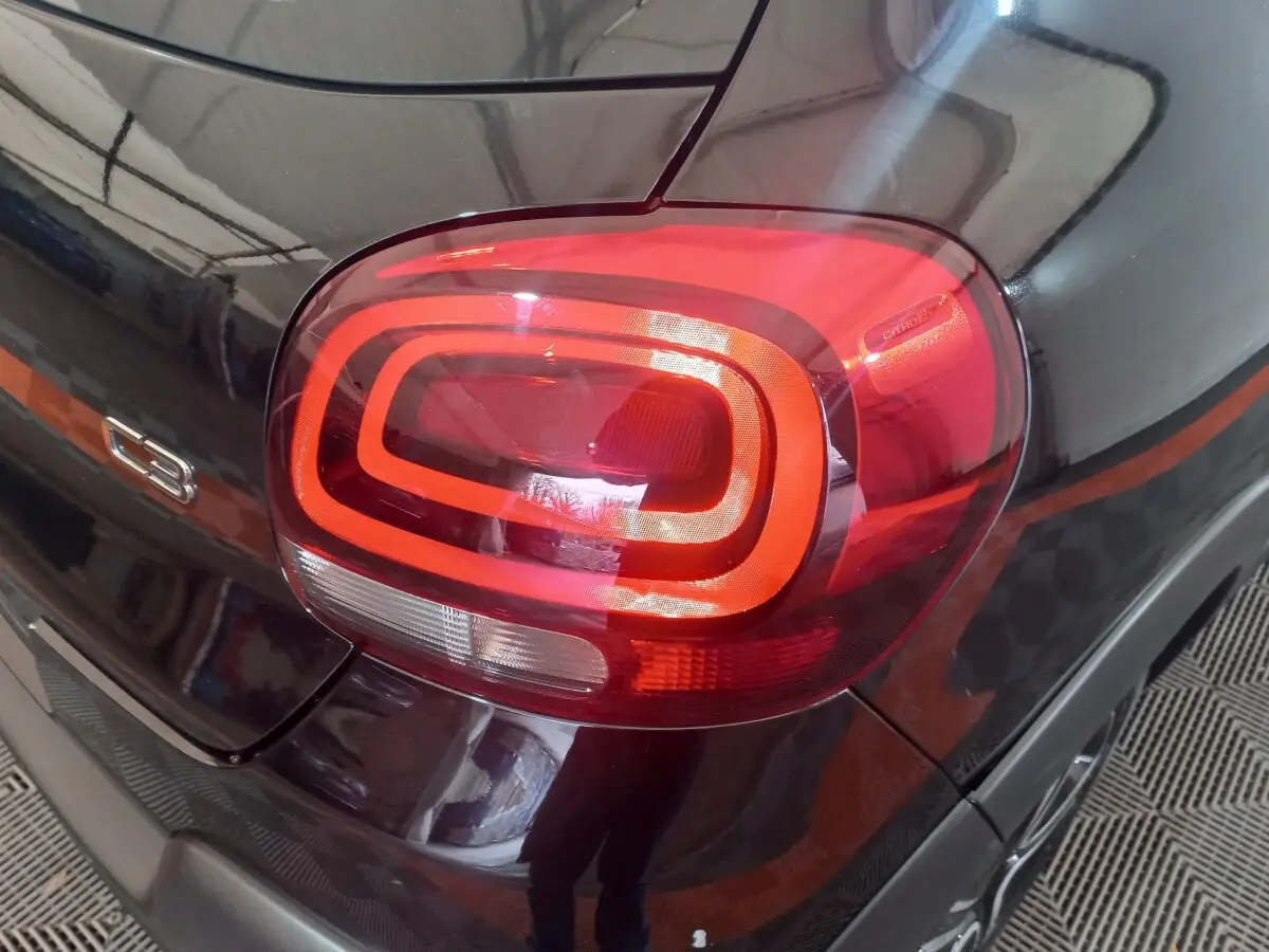 Gros plan sur le feu arrière droit rouge et noir brillant d'une Citroën C3 2024, avec logo et badge C3 visibles.