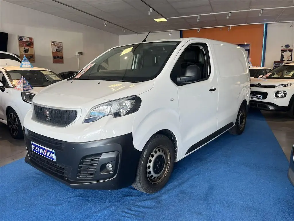 Vue 3/4 avant d'un Peugeot Expert Fourgon blanc avec pare-chocs noir dans un showroom.