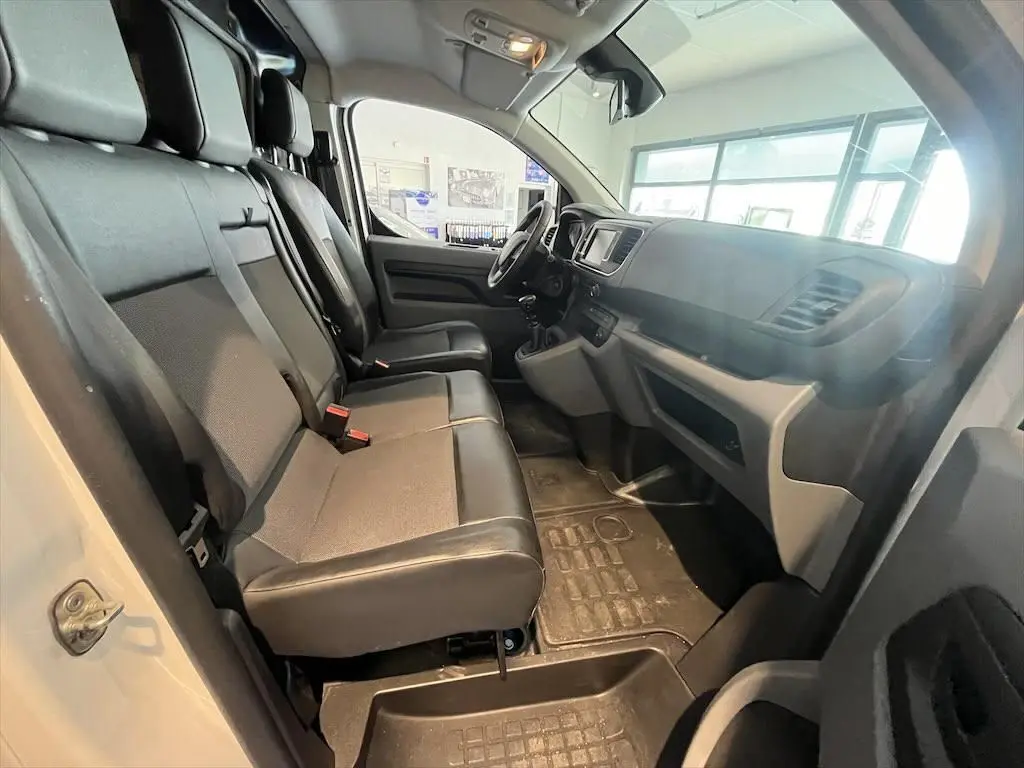 Vue intérieure côté conducteur du Peugeot Expert Fourgon blanc 2019, sièges avant modulables en tissu gris et noir.