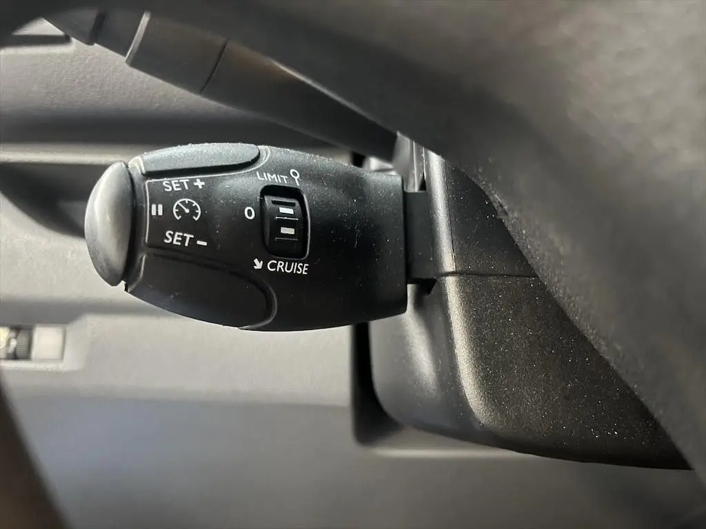 Gros plan sur la commande de régulateur de vitesse noire du Peugeot Expert Fourgon blanc, côté conducteur.