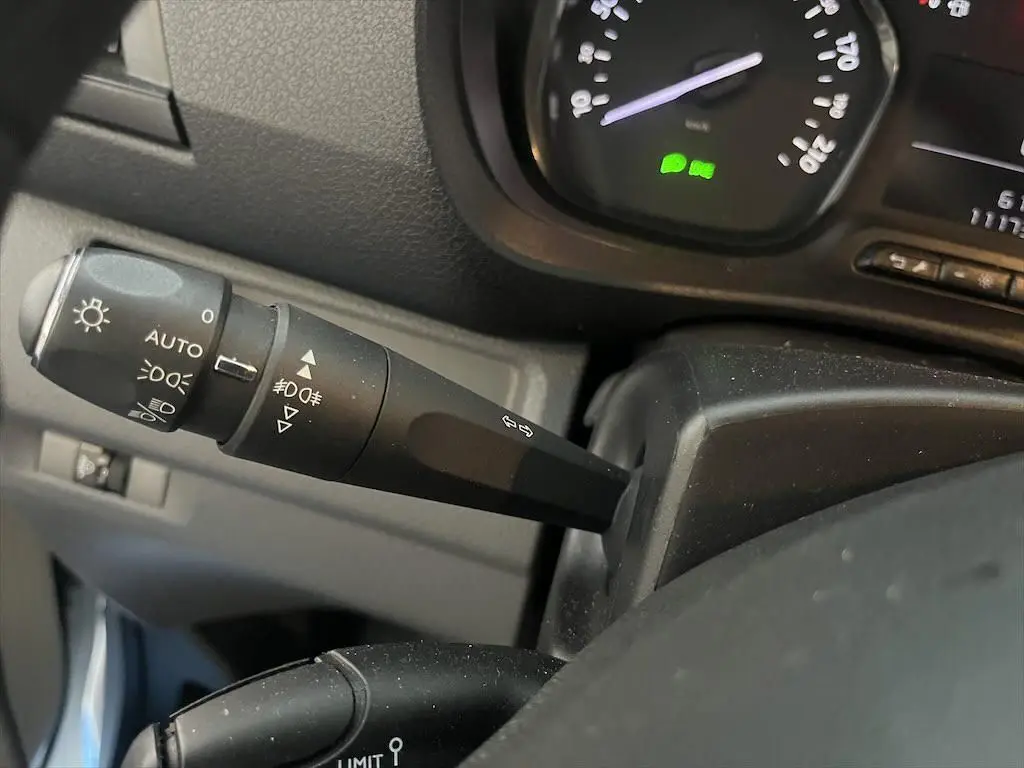 Gros plan sur la commande des phares et clignotants à gauche du volant dans un Peugeot Expert Fourgon blanc 2019.