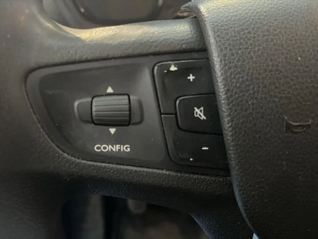 Gros plan sur les commandes noires du volant du Peugeot Expert Fourgon blanc, avec bouton config et réglage volume.