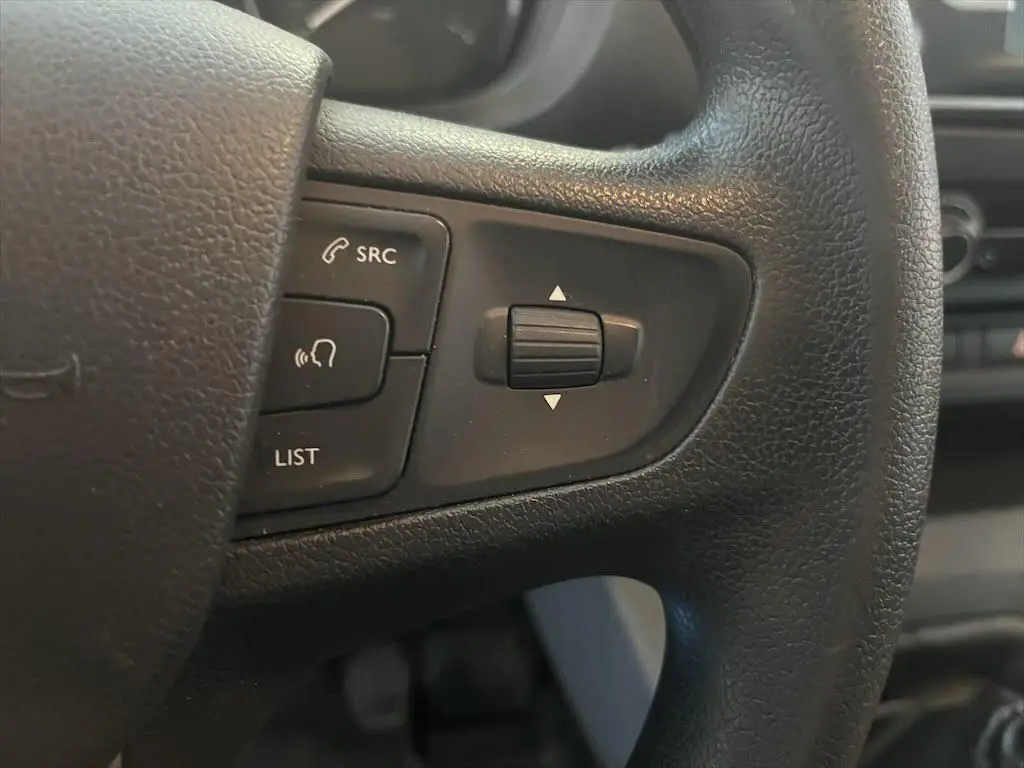 Gros plan sur les commandes audio au volant noir du Peugeot Expert Fourgon blanc, version 2019, côté gauche.
