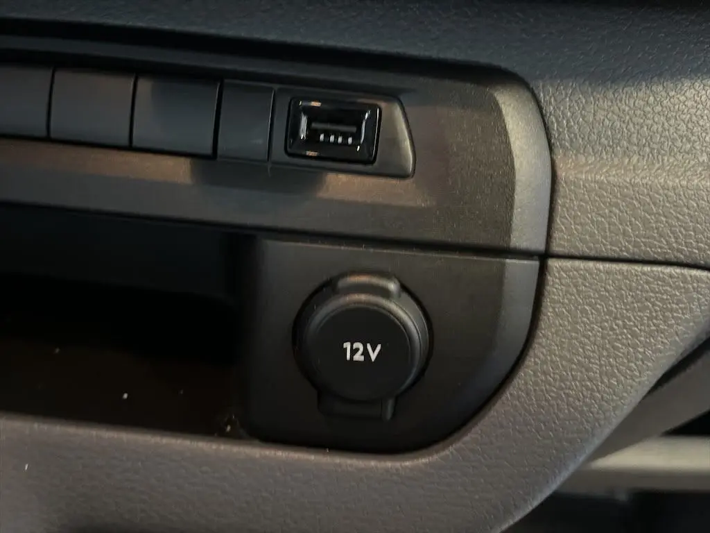 Gros plan sur la prise 12V et port USB du tableau de bord noir du Peugeot Expert Fourgon blanc de 2019.