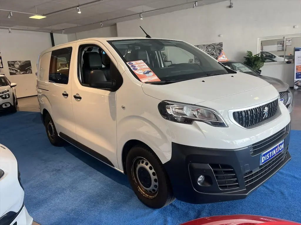 Peugeot Expert Fourgon blanc vu en 3/4 avant droit dans un showroom avec pare-chocs noir et jantes acier.
