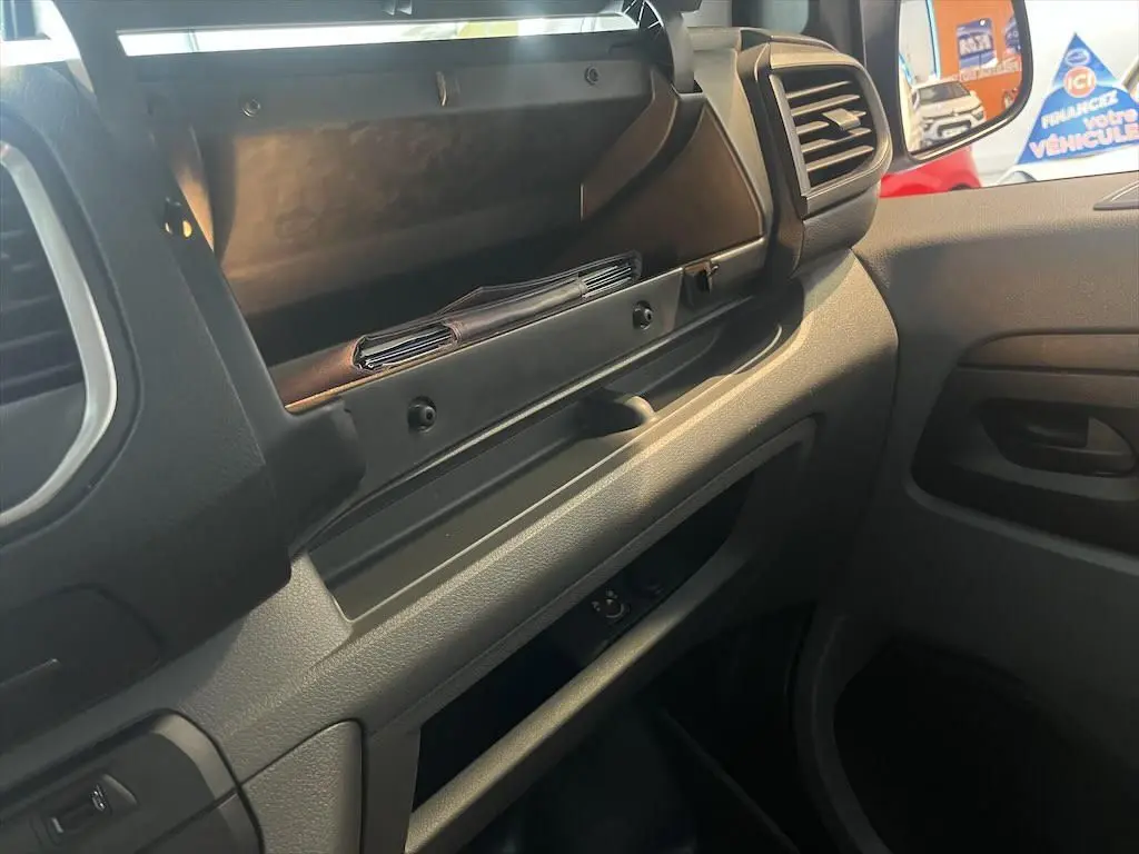 Vue intérieure côté passager du Peugeot Expert Fourgon blanc 2019, avec boîte à gants ouverte et tableau de bord gris noir.