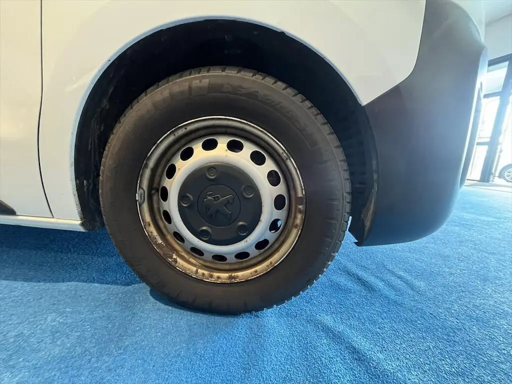 Gros plan sur la roue avant droite du Peugeot Expert Fourgon blanc, avec jante acier et logo Peugeot au centre.
