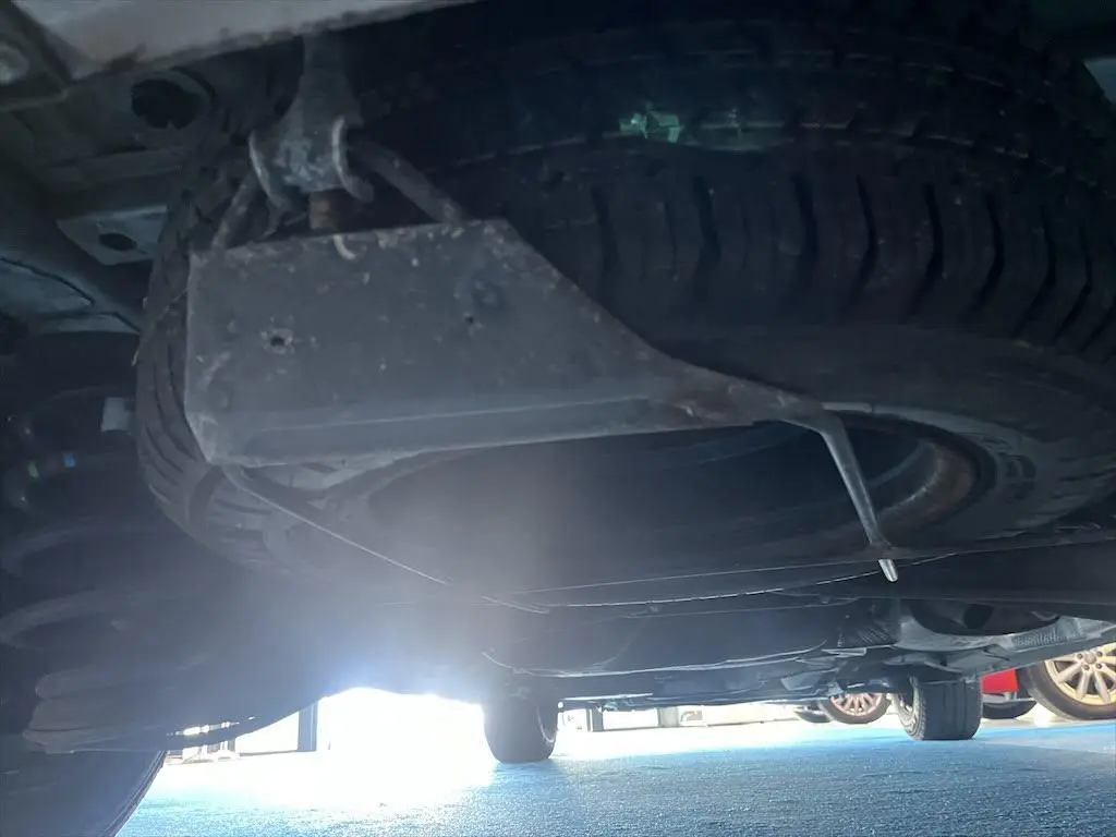 Vue sous le Peugeot Expert Fourgon blanc montrant la roue de secours suspendue sous le châssis arrière.