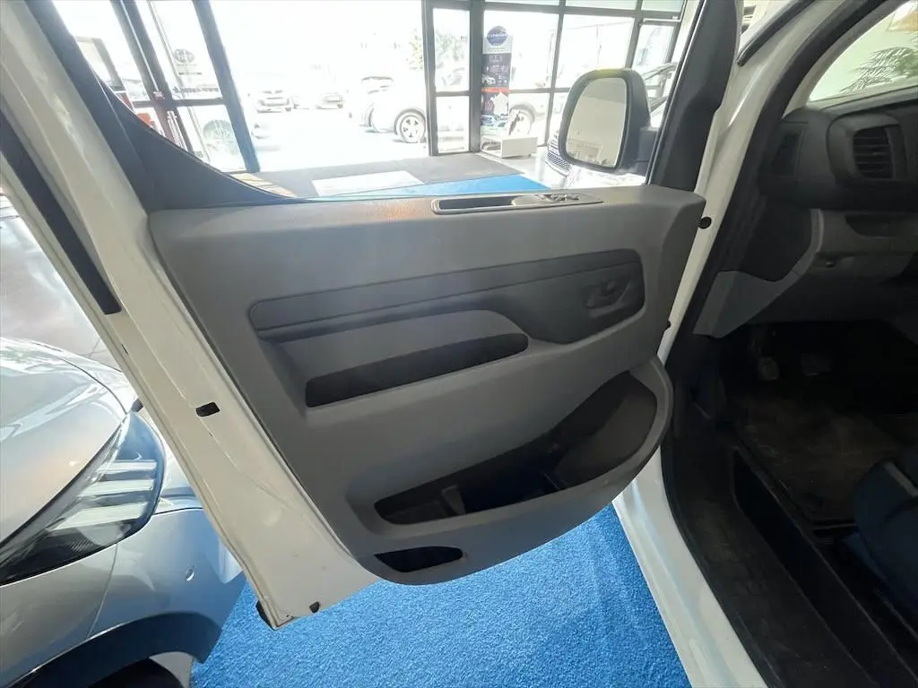 Vue intérieure de la porte avant gauche du Peugeot Expert Fourgon blanc, montrant les rangements et la poignée.