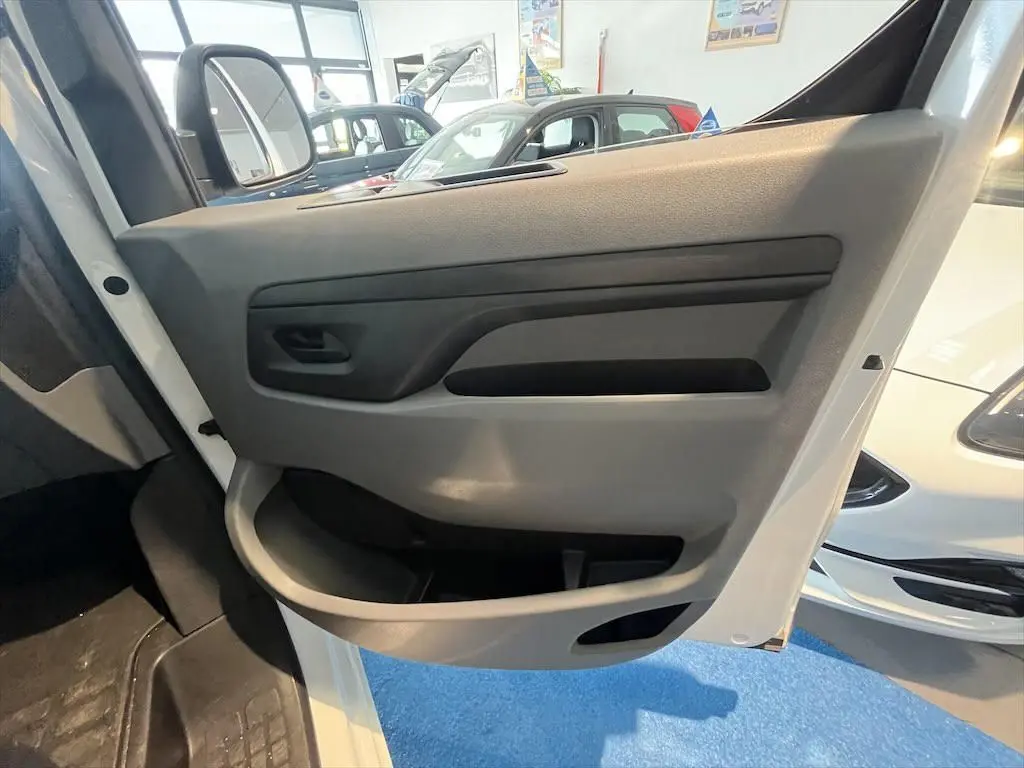 Vue rapprochée de la porte avant gauche blanche du Peugeot Expert Fourgon 2019, intérieur gris avec poignée noire.