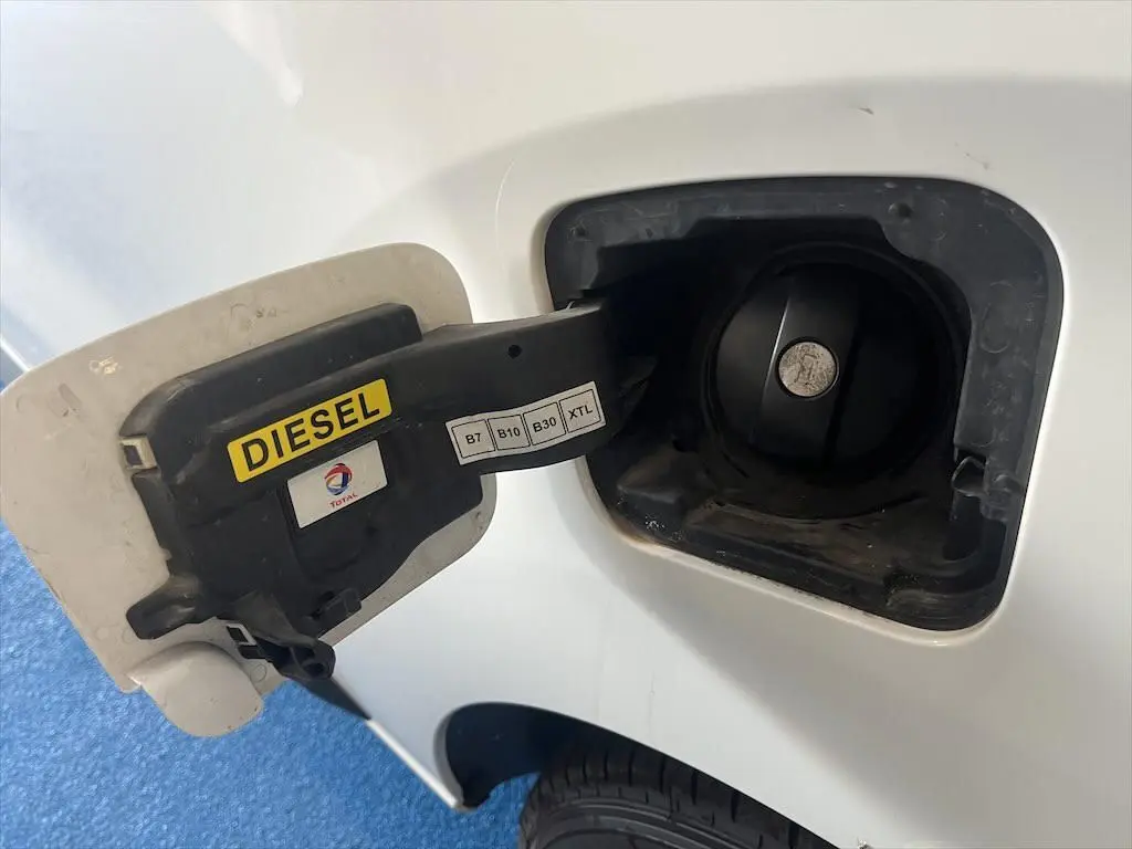 Bouchon de réservoir diesel ouvert côté gauche d'un Peugeot Expert Fourgon blanc, avec étiquette jaune "DIESEL".
