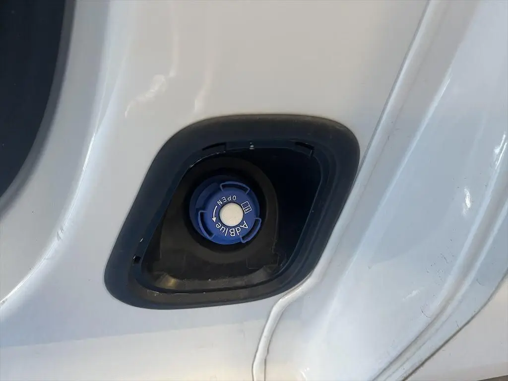 Gros plan sur le bouchon bleu AdBlue du Peugeot Expert Fourgon blanc, situé dans l'encadrement de porte.