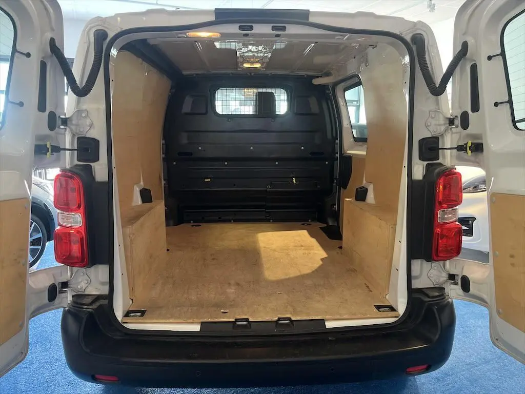 Vue arrière intérieure du Peugeot Expert Fourgon blanc 2019, montrant l'espace de chargement avec parois en bois et cloison métallique.