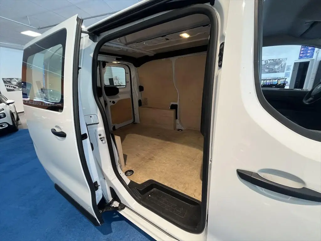 Vue latérale droite du Peugeot Expert Fourgon blanc 2019 avec porte coulissante ouverte montrant l'espace de chargement vide en bois clair.
