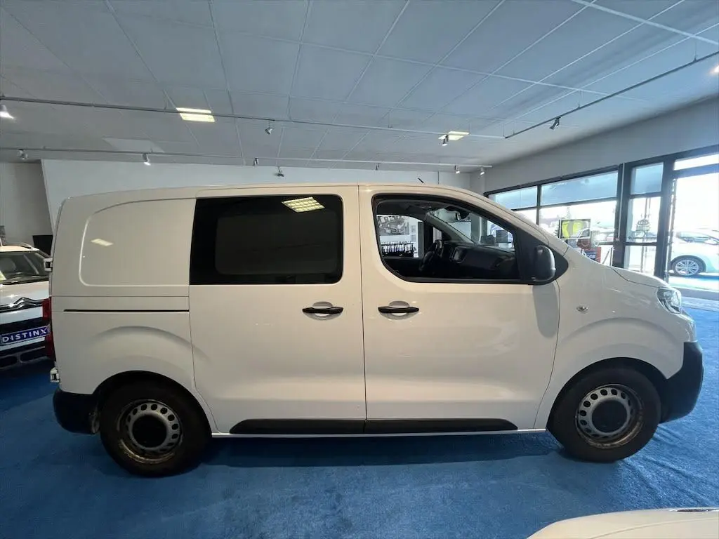 Profil côté gauche d'un Peugeot Expert Fourgon blanc 2019 en intérieur, avec fenêtres teintées et jantes acier.