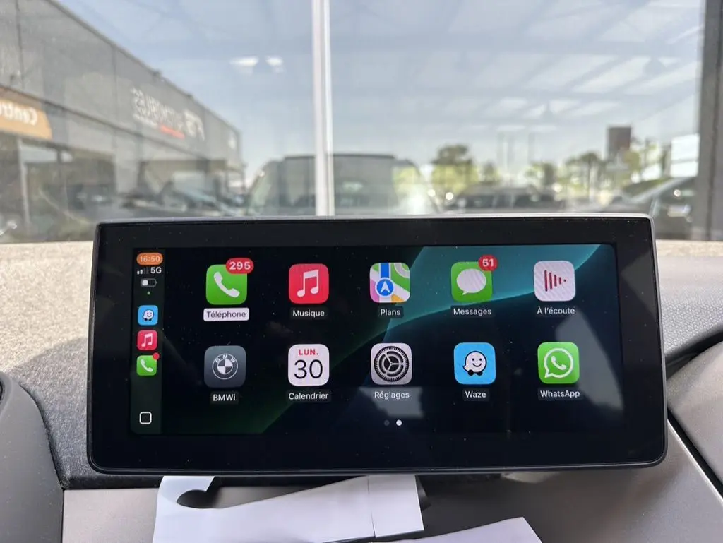 Écran tactile central de la BMW i3 2022 bleu, affichant les applications connectées en intérieur jour.