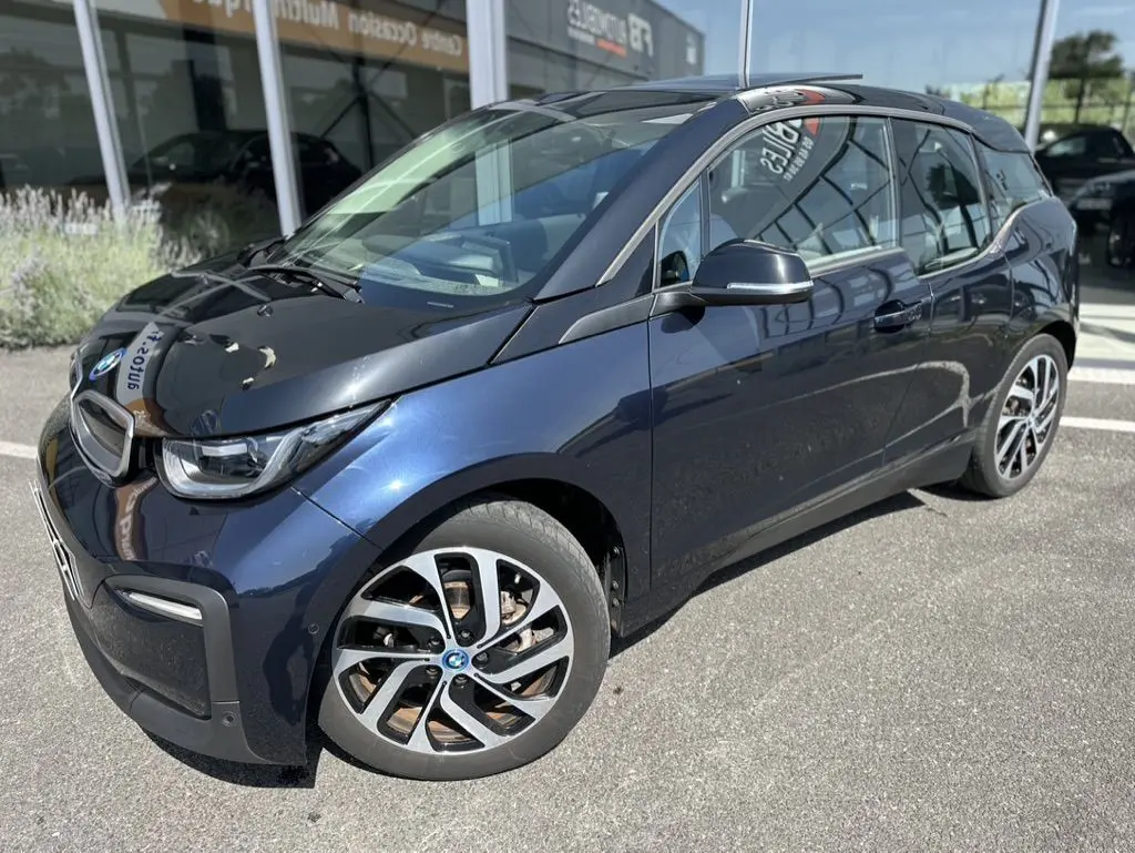 Vue 3/4 avant droite d'une BMW i3 électrique bleue 2022 avec jantes distinctives et toit noir brillant.