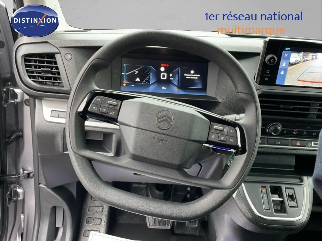 Vue intérieure centrée sur le volant et tableau de bord du Citroën Jumpy gris avec écran tactile et caméra de recul.