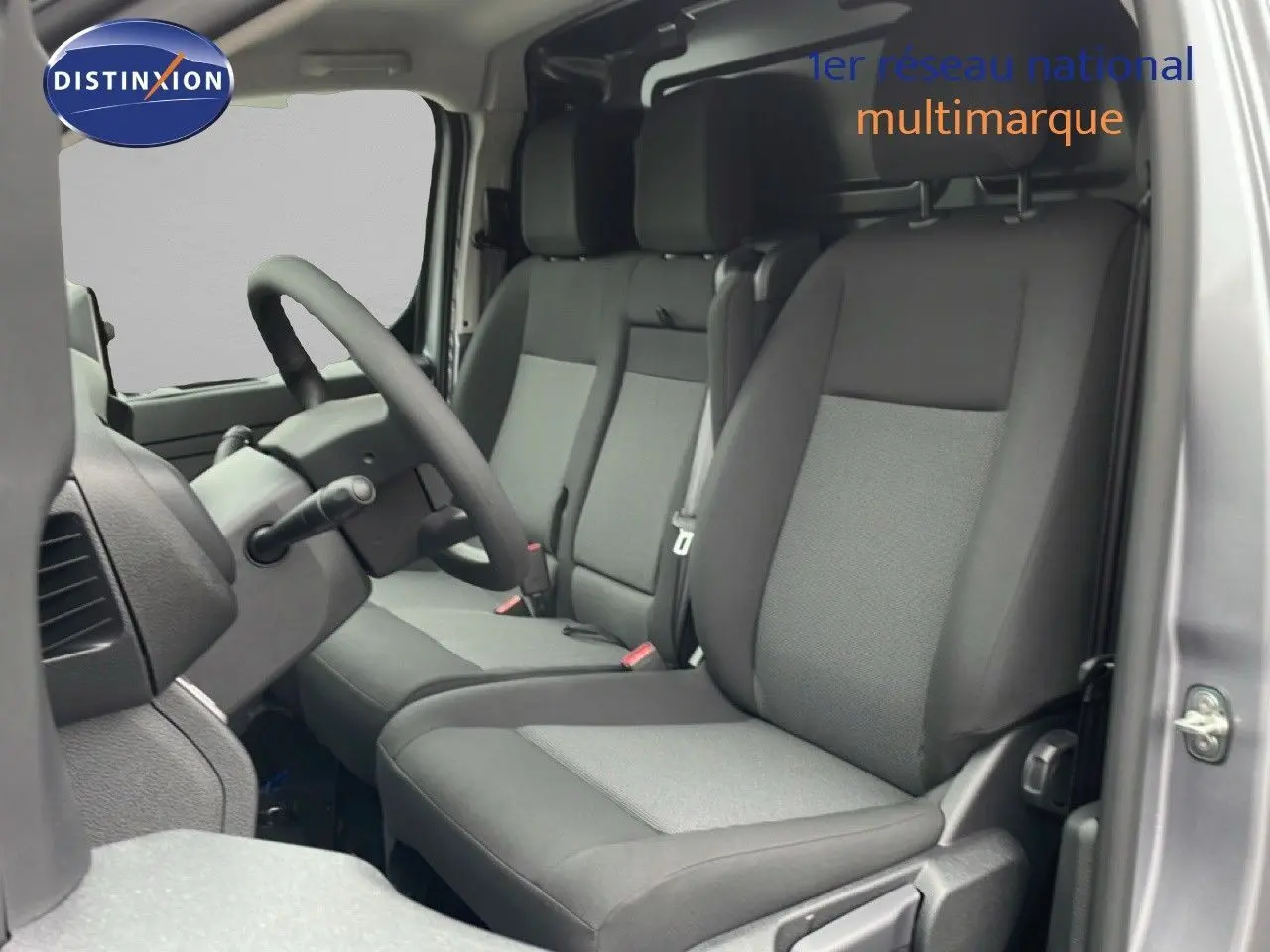 Intérieur du Citroën Jumpy gris Artense, vue côté conducteur montrant les sièges tissu bicolores et le volant multifonction.