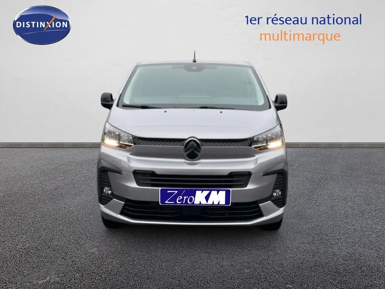 Vue frontale du Citroën Jumpy gris Artense métal 2025 avec calandre distinctive et feux allumés.