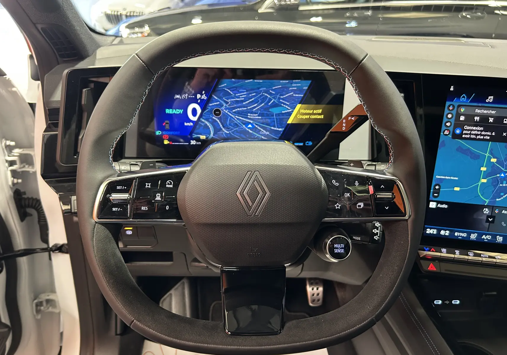 Vue rapprochée du volant noir du Renault Austral Ph.2 avec tableau de bord numérique et écran tactile central allumé.