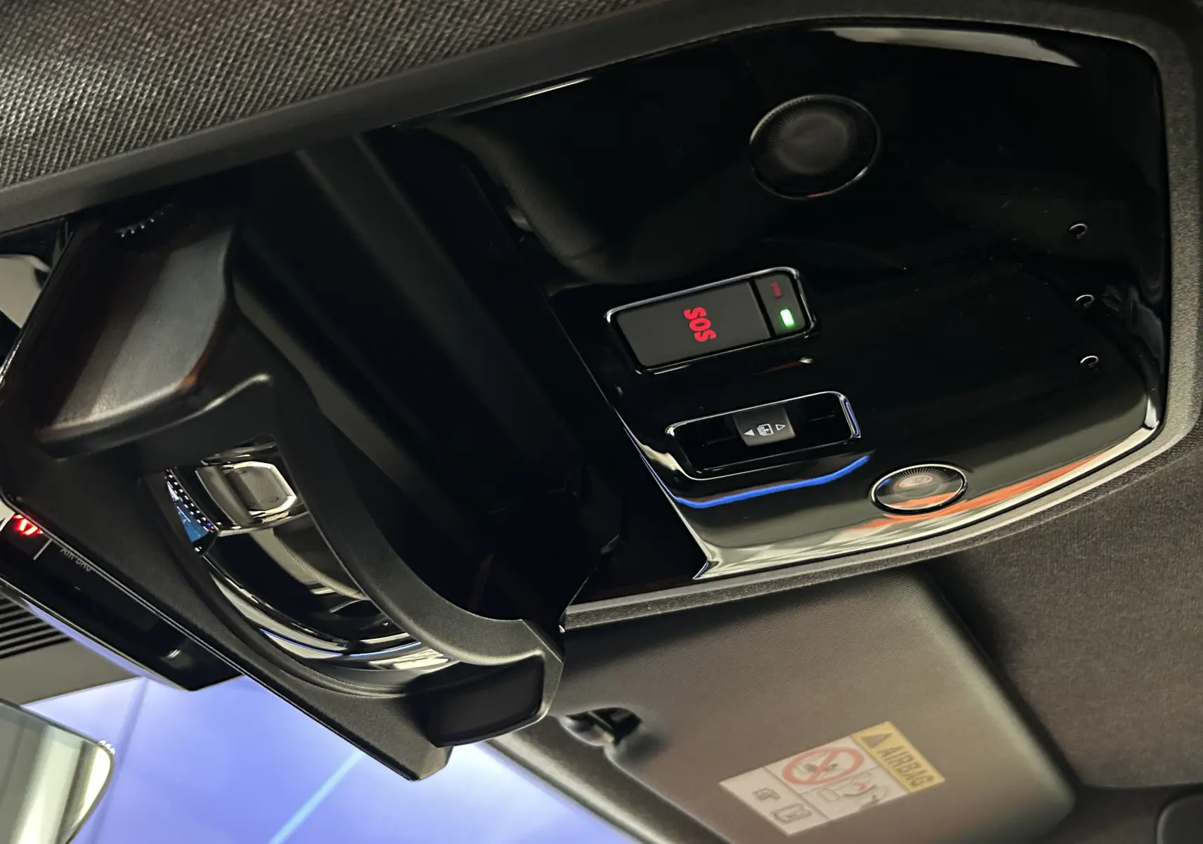 Vue intérieure en plongée sur le plafonnier noir brillant avec bouton SOS et compartiment lunettes ouvert du Renault Austral blanc nacré.