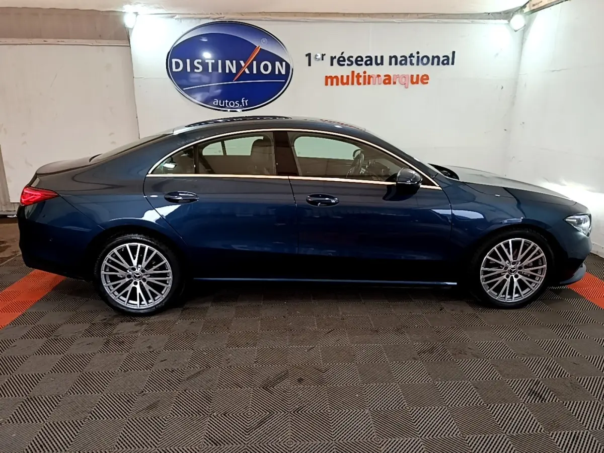 Vue latérale droite d'une Mercedes Classe CLA bleu foncé avec jantes alliage multi-branches en intérieur showroom.