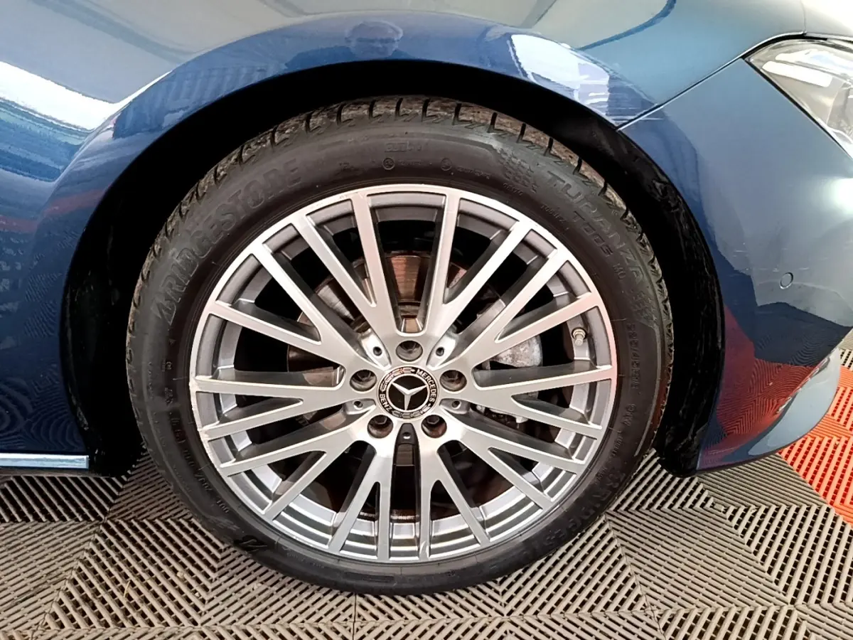 Gros plan sur la jante alu argentée et pneu Bridgestone d'une Mercedes CLA 180 d Business Line bleu foncé, côté avant droit.