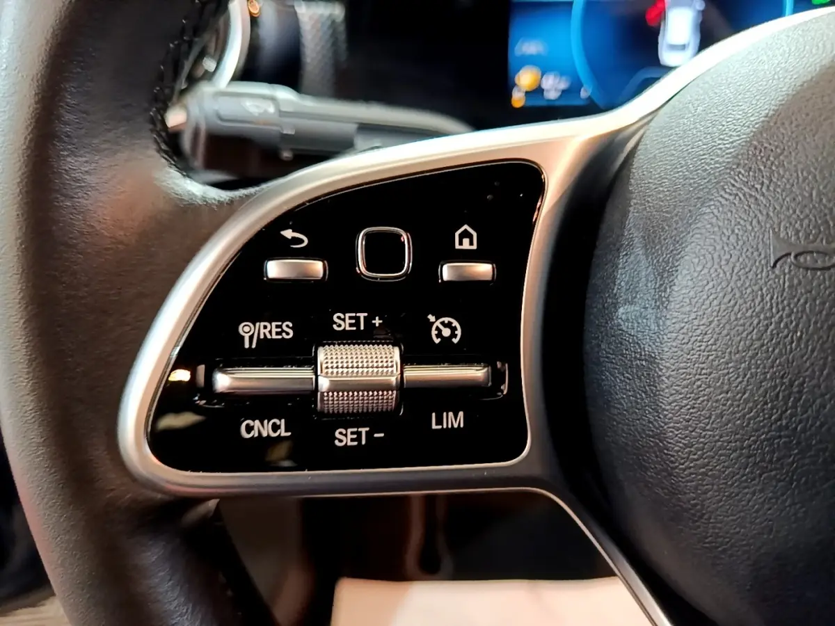Gros plan sur les commandes multifonctions en alu et cuir du volant côté gauche d’une Mercedes CLA 180 d Business Line 2021.