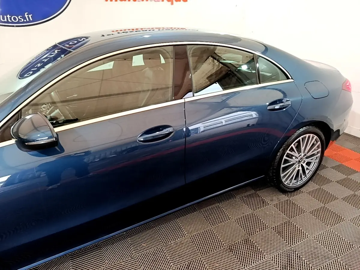 Vue latérale droite d'une Mercedes Classe CLA bleu métallisé avec jantes alliage multi-branches dans un showroom.