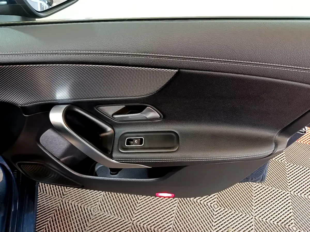 Vue rapprochée de la porte côté gauche noire de la Mercedes CLA 180 d Business Line avec poignée alu et bouton de vitre électrique.