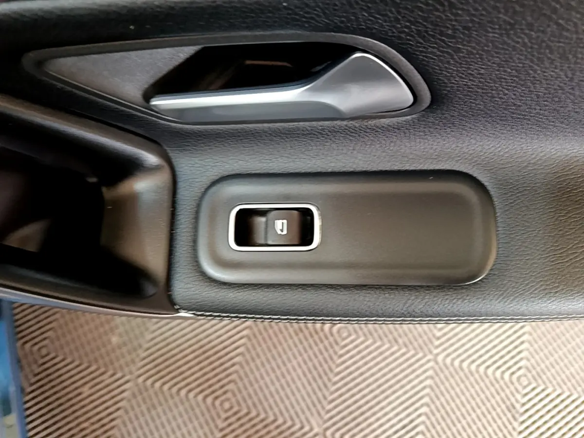 Gros plan sur le bouton de commande de la vitre côté conducteur de la Mercedes CLA 180 d Business Line blanche.