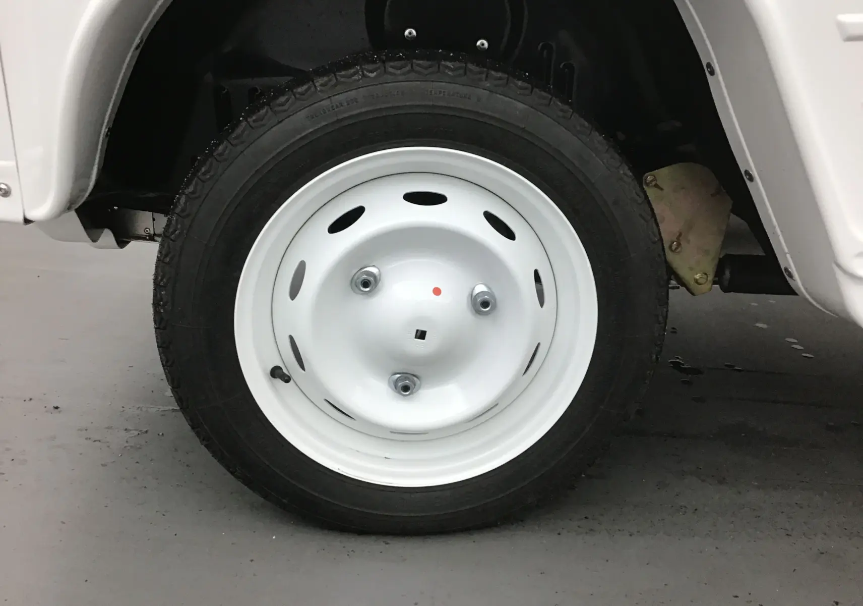 Gros plan sur la roue avant droite blanche du MLT E-STORY ICONE 2024, avec jante acier classique et pneu noir.