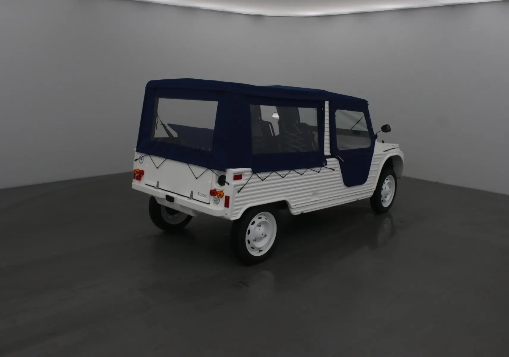 Vue 3/4 arrière droite du MLT E-STORY ICONE blanc avec toit et portes souples bleu foncé, style Méhari électrique.