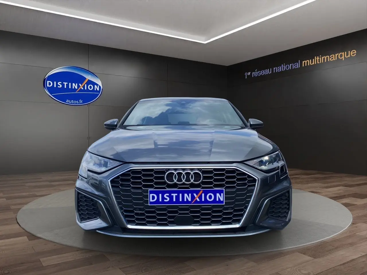 Vue frontale d'une Audi A3 Sportback 30 TFSI S-Line gris Daytona avec calandre hexagonale et phares LED allumés.