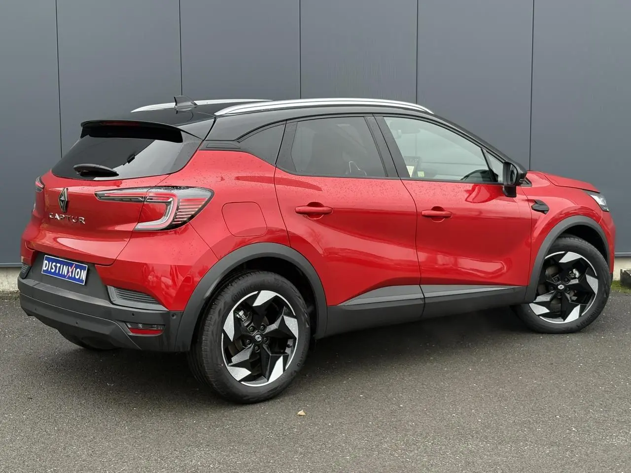 Vue 3/4 arrière droite du Renault Captur 2025 rouge Flamme avec toit noir et jantes alu diamantées noires.