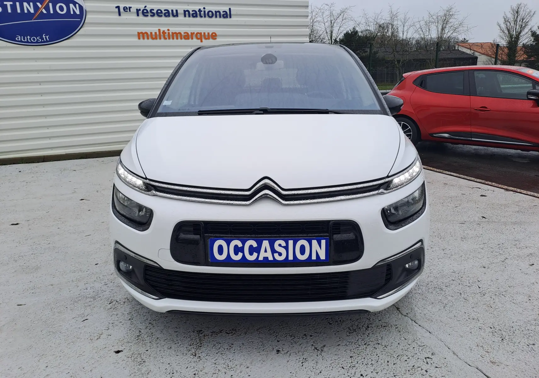 Vue avant d'une Citroën C4 Spacetourer blanche avec plaque "OCCASION" sur un parking extérieur.