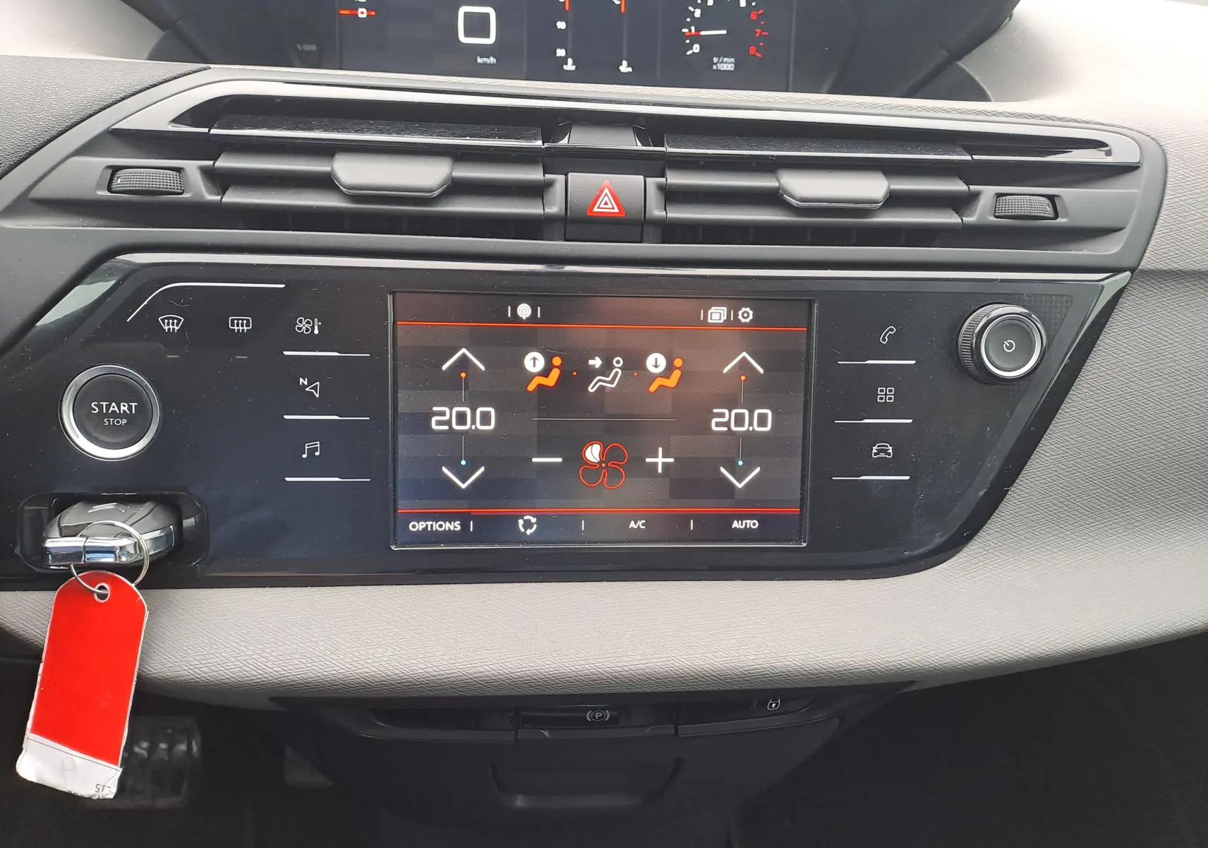 Vue rapprochée du tableau de bord noir du Citroën C4 Spacetourer 2018 avec écran tactile de climatisation et bouton start/stop.