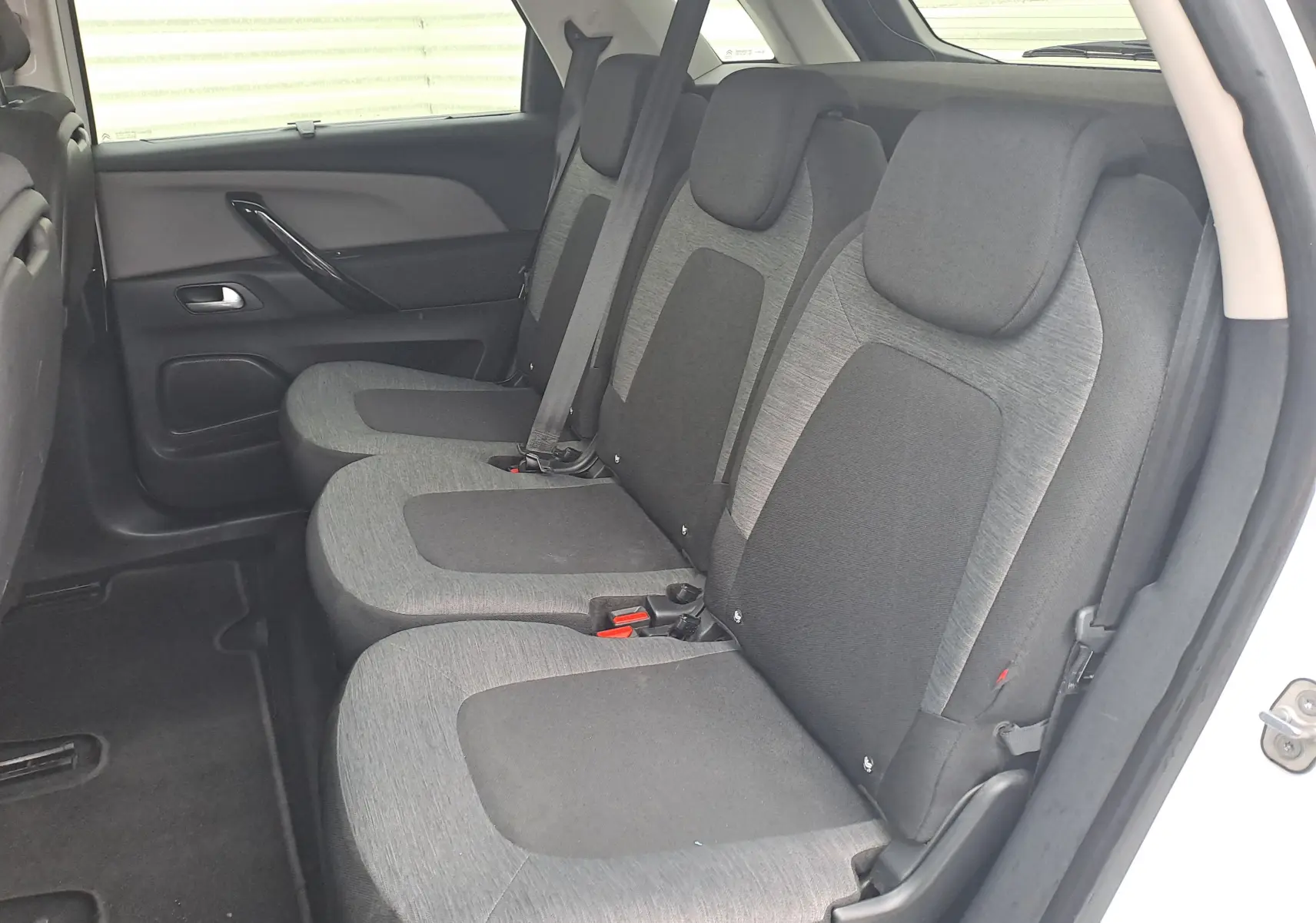 Vue latérale droite de l'intérieur arrière du Citroën C4 Spacetourer blanc, montrant les sièges tissu bicolores gris et noir.